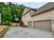 Home exterior showcasing a three car garage, basketball court and lush landscaping at 5250 Briarstone Ridge Way, Alpharetta, GA 30022