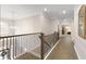 Hallway with hardwood floors, metal railing, and views into other rooms of the house at 5250 Briarstone Ridge Way, Alpharetta, GA 30022