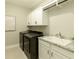 Laundry room featuring black washer and dryer, white cabinets, granite countertops, and a white porcelain sink at 5250 Briarstone Ridge Way, Alpharetta, GA 30022