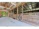 This barn interior features stalls with wood beams and a concrete floor with an outdoor view at 1200 Old Lathemtown Rd, Canton, GA 30115