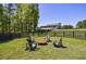 An outdoor fire pit area surrounded by lush trees with black Adirondack chairs in the back yard at 1200 Old Lathemtown Rd, Canton, GA 30115