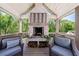 Covered porch with a striking brick fireplace, wood storage, and comfortable seating with a wooded view at 1200 Old Lathemtown Rd, Canton, GA 30115
