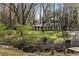Brick home with lush front yard showcasing mature trees, creek, and landscaping at 1351 Stephens Sw St, Lilburn, GA 30047