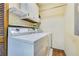 Bright laundry room with washer, dryer, shelves, and cream-colored walls at 1351 Stephens Sw St, Lilburn, GA 30047