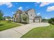 View of a two-story home showing the large driveway and 3-car garage, surrounded by green lawn at 2127 Harmony Dr, Canton, GA 30115