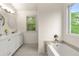 Bright bathroom with double sink vanity, large window, and soaking tub with modern fixtures at 4805 Wilkie Nw Way, Acworth, GA 30102