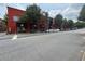 Exterior street view of a red building with commercial spaces, scooters, and cars parked along the roadside at 172 Haynes Sw St # 107, Atlanta, GA 30313