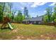 Exterior backyard view featuring a play set, covered patio, and a wooden fence at 60 Water Oak Trl, Covington, GA 30014