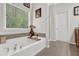 Bathroom featuring a large soaking tub with tile surround and a large window at 1076 Firethorne Pass, Cumming, GA 30040