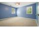 Bedroom with neutral carpet, blue walls, ceiling fan, and two windows with views of the outside at 2795 Autumn Dr, Canton, GA 30115