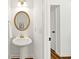 Powder room features a pedestal sink, round mirror, and gold fixtures at 5395 Fontenoy Ct, Peachtree Corners, GA 30071