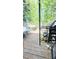 This wooden deck is surrounded by trees, and includes chairs, a small table, grill, and plants at 4256 Village Square Ln, Stone Mountain, GA 30083