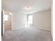 A bright bedroom with neutral carpet, a window, and a door leading to an additional room at 632 Eagles Nest Cir, Auburn, GA 30011