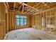 Unfinished bedroom with exposed framing, wiring and large windows overlooking the yard at 120 Wood River Ct, Johns Creek, GA 30097