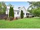 Angle view of the home's exterior showing the metal roof, siding, and ample landscaping with green lawn at 1830 Lost Mountain Rd, Powder Springs, GA 30127