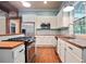 Kitchen features white cabinets, stainless steel appliances, and butcher block countertops with natural light at 1830 Lost Mountain Rd, Powder Springs, GA 30127