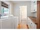 A laundry room with hardwood flooring, a window, modern washer and dryer and ample cabinetry at 1830 Lost Mountain Rd, Powder Springs, GA 30127