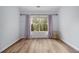 Light and airy bedroom with wood-look flooring and stylish curtains framing a view of lush greenery at 218 3Rd Ave, Avondale Estates, GA 30002