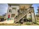 Back of house with wooden stairs leading to an upper covered patio, hot tub on lower patio at 544 Pine Way, Dallas, GA 30157