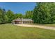 Ranch style home featuring an attached garage and a long concrete driveway on a vast green lawn surrounded by trees at 70 Graystone Dr, Covington, GA 30014