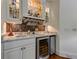 Modern bar with granite countertops, mosaic tile backsplash, wine fridge, and glass shelving for glassware at 8710 Merion Dr, Duluth, GA 30097