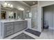 Bathroom featuring a double vanity, marble shower, and gray cabinets at 8710 Merion Dr, Duluth, GA 30097