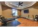 Bright home gym featuring ceiling fan, television, hardwood floors and workout equipment at 8710 Merion Dr, Duluth, GA 30097