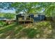 Home's backyard with a wooden deck, a lush green lawn, and mature trees at 1675 Avon Sw Ave, Atlanta, GA 30311
