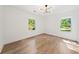 Bright bedroom featuring hardwood floors, two windows, white walls, and a modern light fixture at 1675 Avon Sw Ave, Atlanta, GA 30311