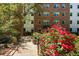 Beautiful condo exterior with brick facade, lush greenery, and vibrant red roses along the walkway at 2965 Pharr Court South Nw # 110, Atlanta, GA 30305