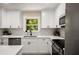 Bright kitchen with white cabinetry, stainless steel appliances, mosaic backsplash, and views to outside at 2358 Larchwood Sw Rd, Atlanta, GA 30310
