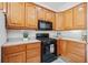 Corner view of a kitchen featuring oak cabinets, white countertops, and black appliances at 675 Jack Page Ln, Canton, GA 30115