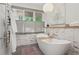 Bright bathroom showcasing a soaking tub, white tile walls, and a large window with natural light and green views at 1255 Cold Harbor Dr, Roswell, GA 30075