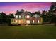 Beautiful two-story brick home with a manicured lawn, mature trees, and inviting front porch at dusk at 100 Coldwater Creek Dr, Mcdonough, GA 30252