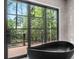 Bathroom with modern black tub and a glass door overlooking the outdoor deck surrounded by greenery at 4366 Skyland Ne Dr, Atlanta, GA 30342