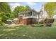 Back exterior featuring a covered deck, tiered landscaping, and lush lawn at 5040 Winding Branch Dr, Dunwoody, GA 30338