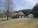 Exterior of the home featuring a two-car garage, shed, and an expansive lawn at 28 County Line #2 Rd, Rydal, GA 30171