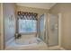 Bright bathroom featuring a jacuzzi tub under a window and a glass-door shower at 3945 Lorien Way, Kennesaw, GA 30152