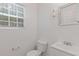 Bright bathroom featuring a window, white fixtures, toilet, vanity, and a framed mirror at 1450 Steam Engine Way, Conyers, GA 30013