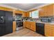 Kitchen featuring wood cabinets, black appliances, tile backsplash, and hardwood floors at 1450 Steam Engine Way, Conyers, GA 30013