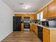 Kitchen view: wooden cabinets, black appliances, tile backsplash, and hardwood floors at 1450 Steam Engine Way, Conyers, GA 30013