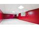 Large finished basement featuring red accent wall, tile ceiling, and carpet flooring at 936 Bramble Oak Ct, Powder Springs, GA 30127