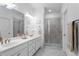 Bright bathroom featuring double sinks, marble floors, and a glass-enclosed shower at 5520 Allegre Pl, Cumming, GA 30028