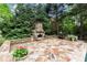 Backyard patio with stone fireplace, stone pavers, and manicured landscaping creates a cozy outdoor retreat at 770 Pine Leaf Ct, Alpharetta, GA 30022