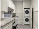 A well-lit laundry room with granite countertop, white cabinets, and stacked washer and dryer at 770 Pine Leaf Ct, Alpharetta, GA 30022