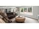Open-concept living room with brown leather couches, large windows, and pool views at 770 Pine Leaf Ct, Alpharetta, GA 30022