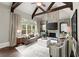 A cozy living room featuring a stone fireplace, large windows, hardwood floors, and a comfortable brown sofa at 770 Pine Leaf Ct, Alpharetta, GA 30022