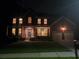 Evening view of a brick home featuring a covered porch, inviting lighting, and a well-kept front lawn at 101 Brendylynn Trce, Woodstock, GA 30188