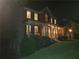 Night view of a two-story brick home with a covered porch and warm interior lighting shining through the windows at 101 Brendylynn Trce, Woodstock, GA 30188