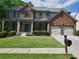 Beautiful two-story brick home featuring a covered front porch, lush lawn, and a convenient two-car garage at 101 Brendylynn Trce, Woodstock, GA 30188